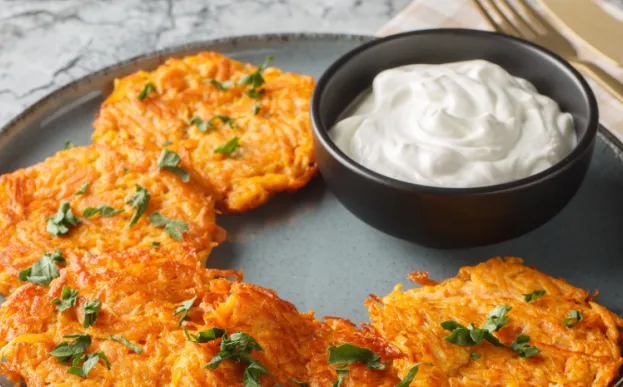 sweet potato pancakes on a plate with sour cream