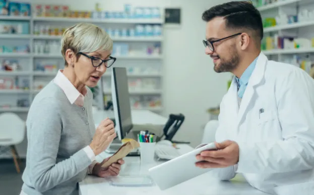 older woman talking to pharmacist about saving money on prescriptions