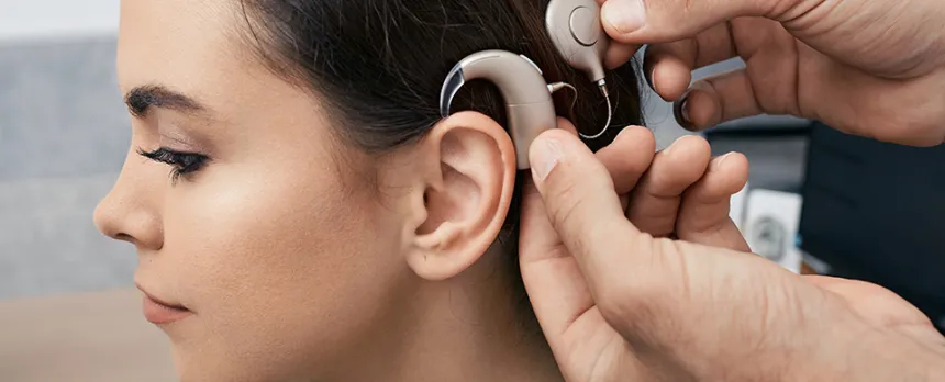 Having recovered from the cochlear implant surgery, a young female patient has her sound processor fitted behind her ear.