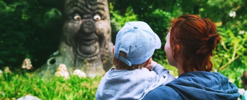 mom holding toddler near tree with a funny face sharing childhood myths