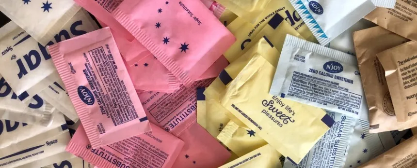 several different colorful sweetener packets on a table