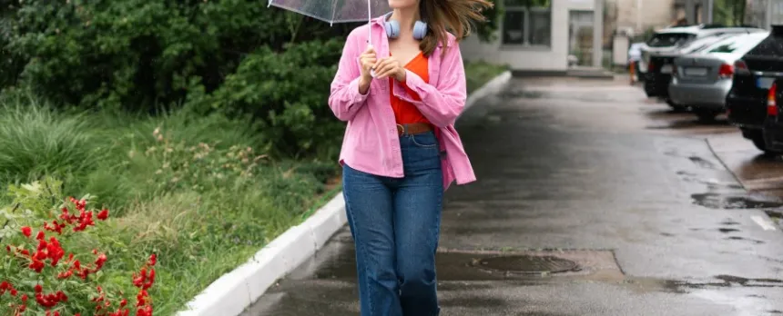 smiling woman walking near a garden with umbrella