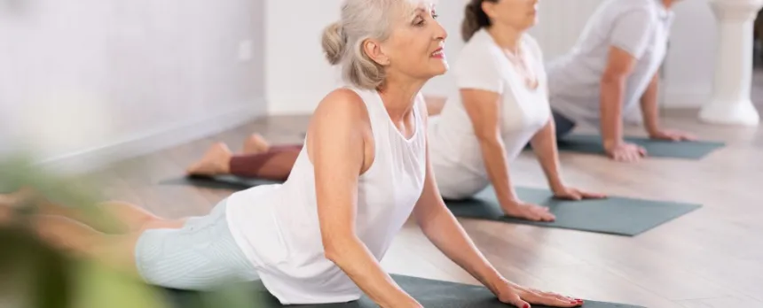 A group of two women and one man practice yoga together.