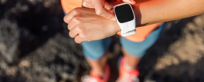 woman outdoors looking at her fitness tracker on her wrist