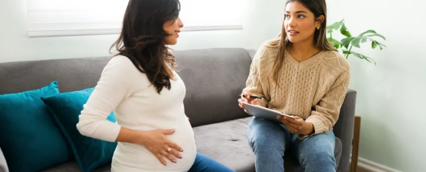 Pregnant woman with a doula sitting on a couch preparing for childbirth.