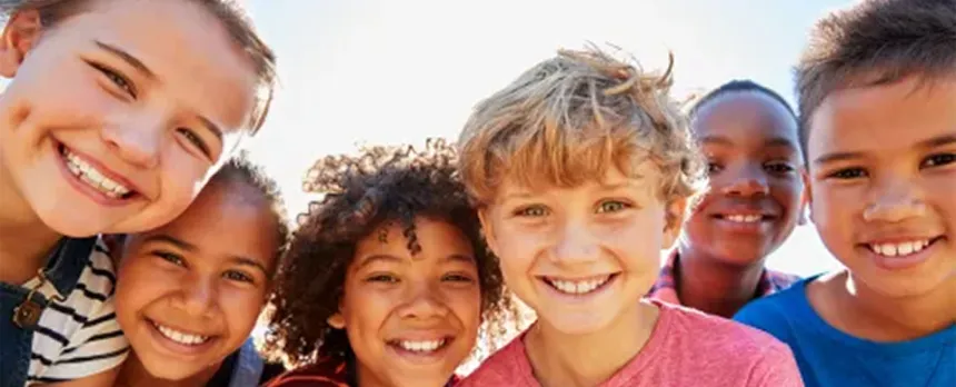 group of kids from diverse backgrounds smiling and playing outside together