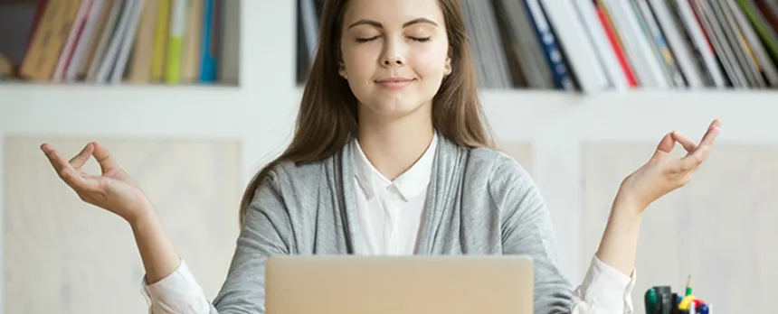 young woman mediating in front of laptop