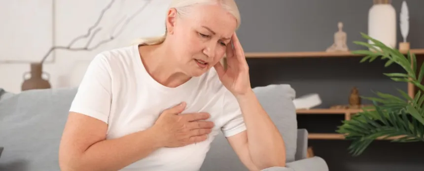 woman on couch holding sore arm caused by lymphedema after cancer.