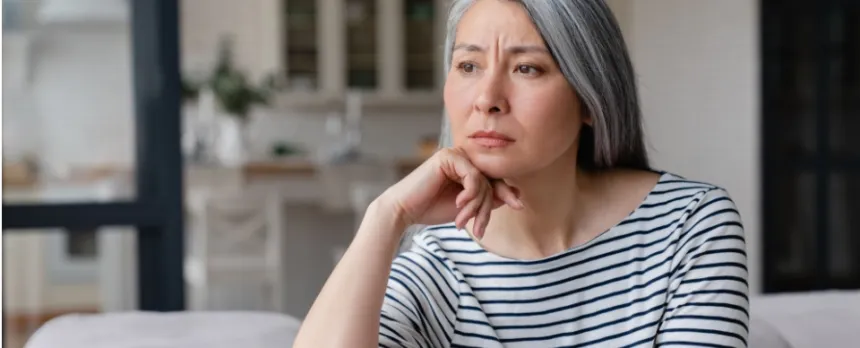 A sad woman staring on a couch needing to improve her mental health