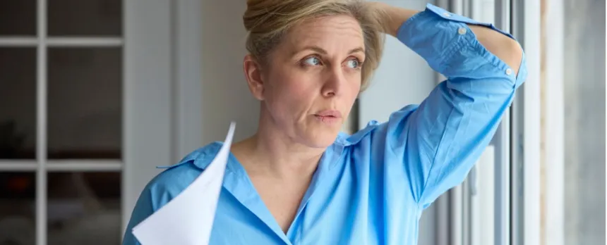 A woman having a hot flash fanning herself trying to manage menopause symptoms