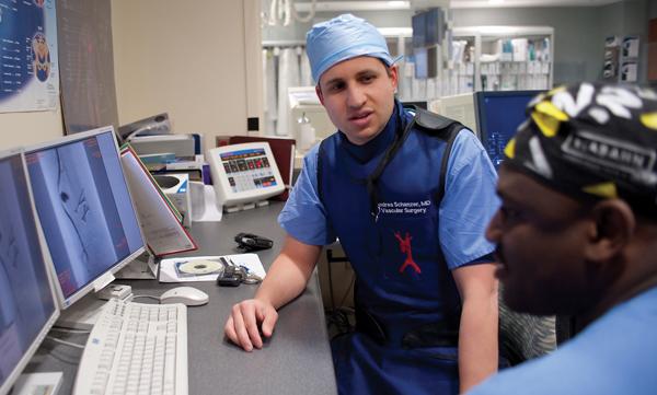 Two doctors are looking at computers during vascular and endovascular services.