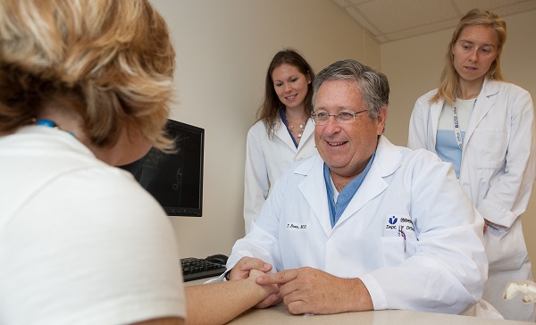 A doctor and medical students are looking at a patient's hand.