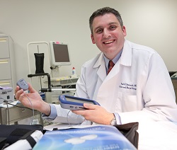 A smiling doctor is holding equipment used for colorectal surgery.