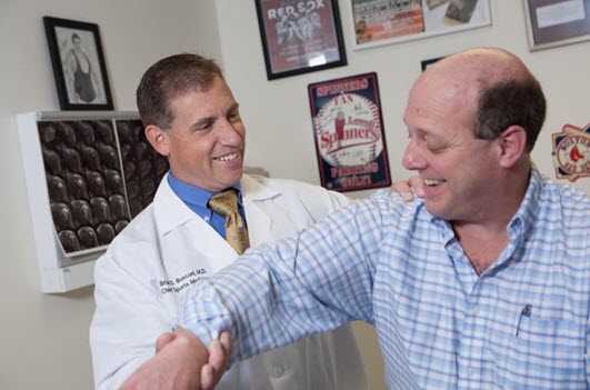 A sports medicine doctor is inspecting the arm of a patient.